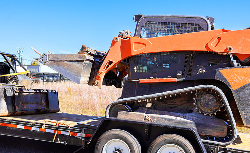 Skid Steer on a trailer being delivered by East County Rentals